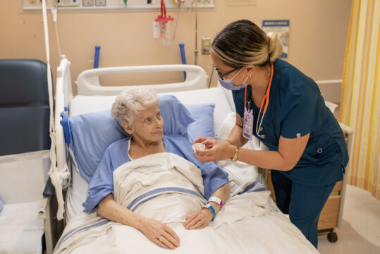 A female nurse assisting an elderly patient.