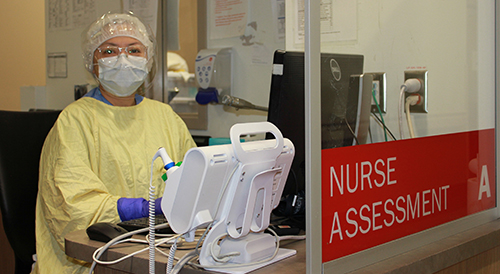 A nurse standing next to a Nurse Assessment sign.