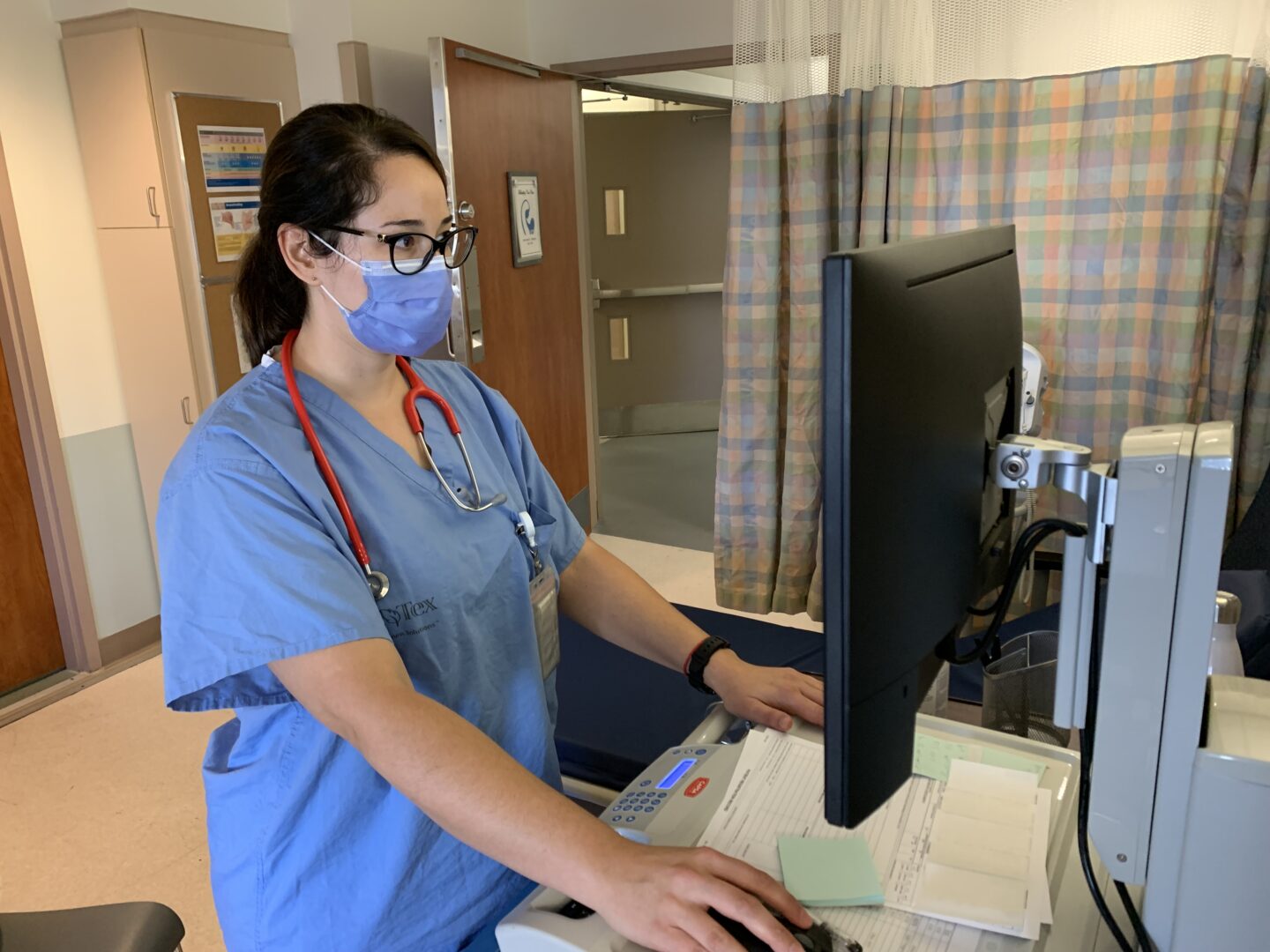 A nurse standing up and working in front of a computer.