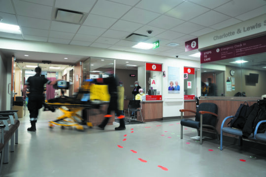 Two emergency health care workers wheel a stretcher into the emergency room.