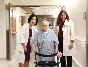 2 healthcare workers walking with an elderly patient