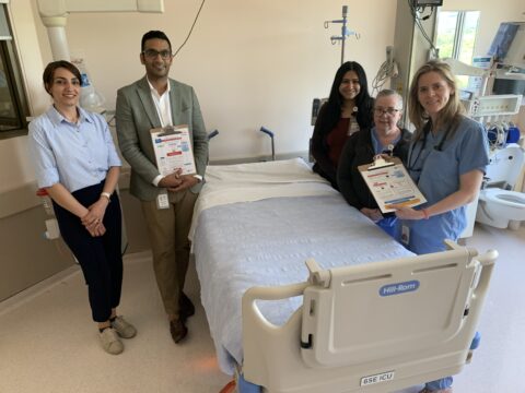 Four females and one male pose around a patient bed holding clipboards showing the ACT-FAST algorithm.